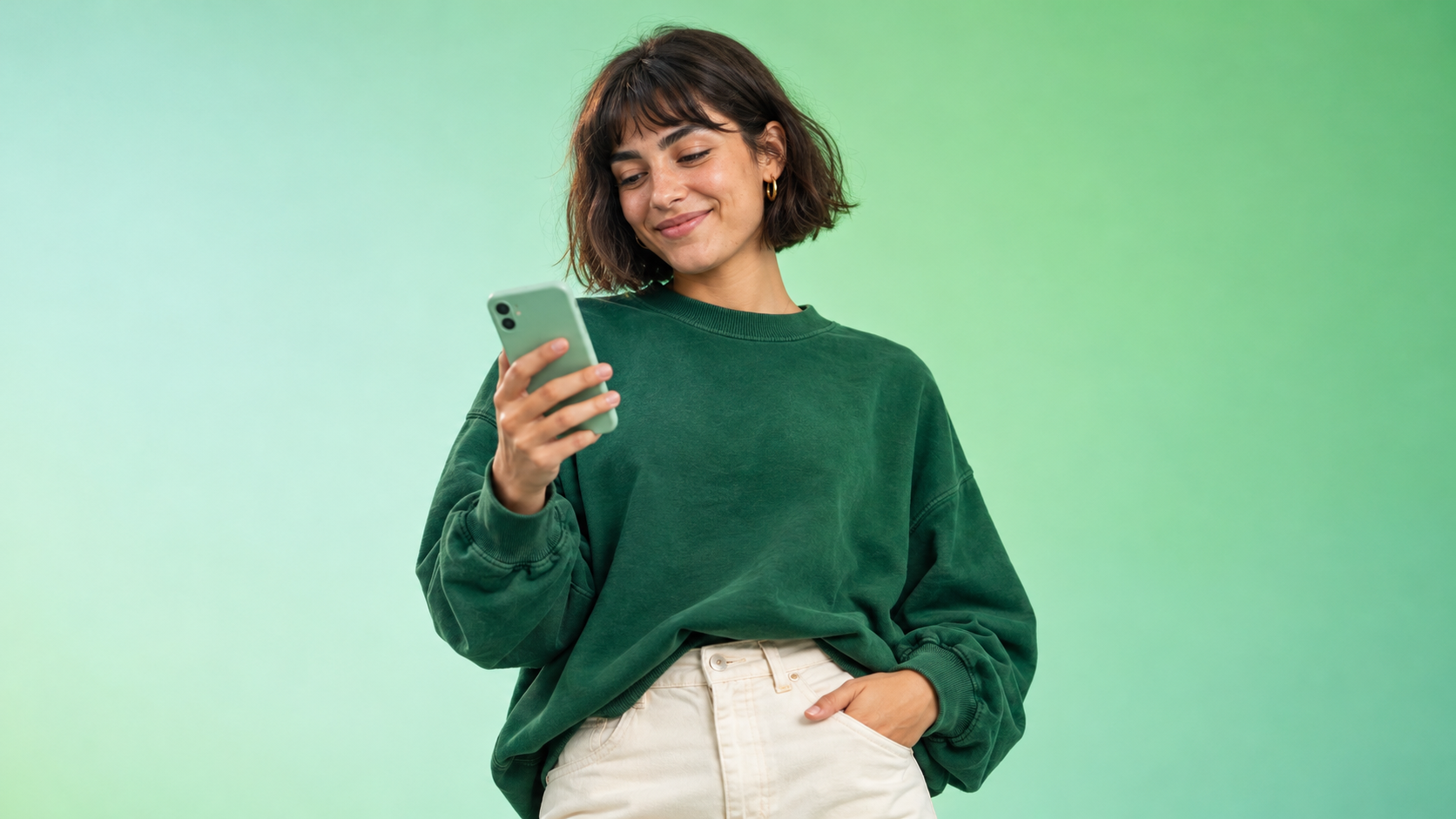 A woman in a green sweater looking at her phone